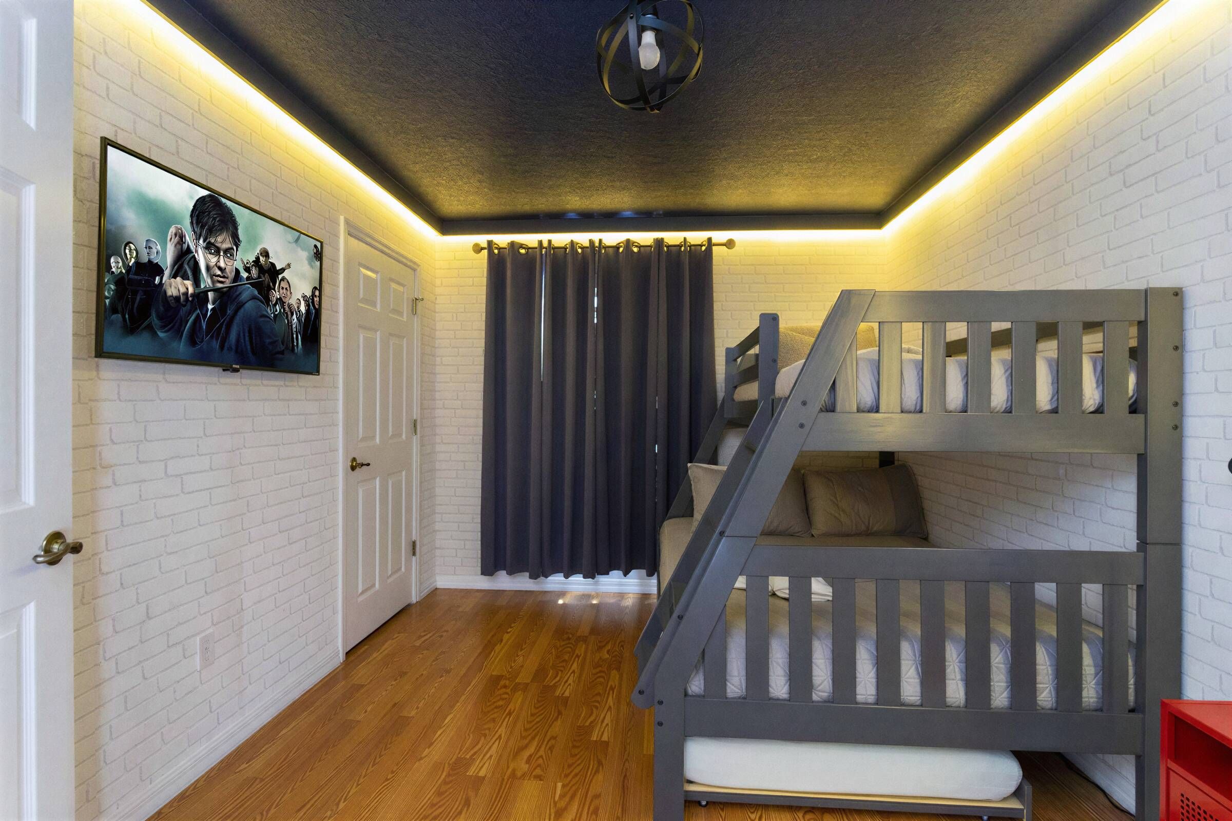 A room with a bunk bed, a door, a wall-mounted picture, and a curtain.