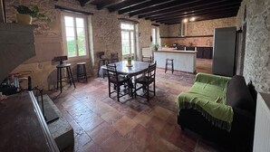 A rustic kitchen with stone walls, a wooden ceiling, and a central island.