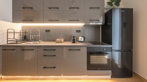 Una cocina moderna con un refrigerador de acero inoxidable, horno empotrado y una encimera con tetera y cesta.