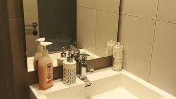 Bathroom features a large mirror above a sink with a shower area and amenities.