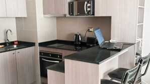 A modern kitchen with a built-in microwave, a coffee maker, and a laptop on a small island. - Urbano Ñuñoa (Santiago)