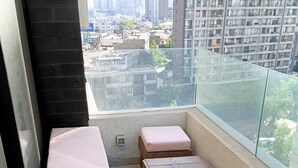 A balcony with wooden benches and cushions, offering a view of a cityscape with high-rise buildings. - Urbano Ñuñoa (Santiago)