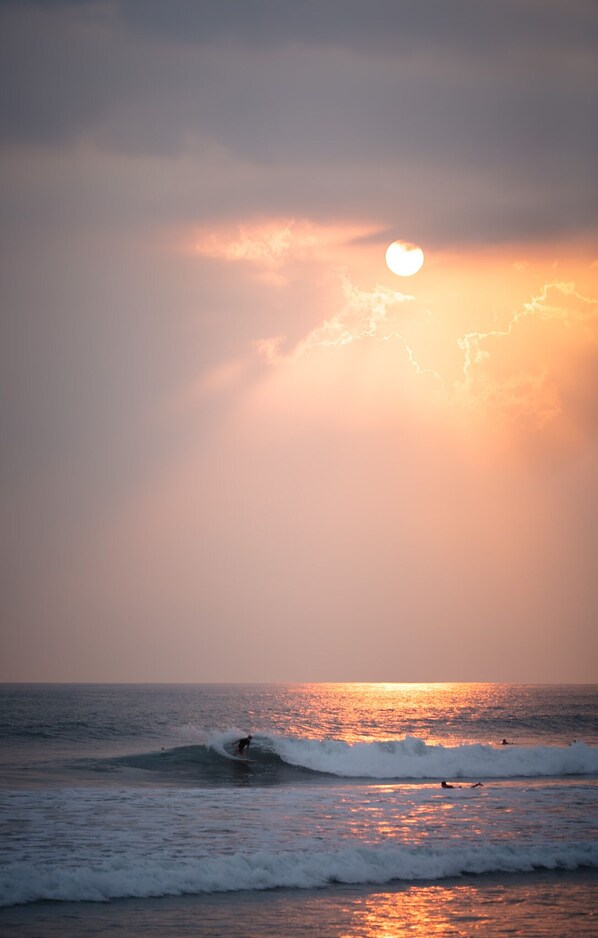 Ein Sonnenuntergang über dem Meer mit Wellen und Surfern.