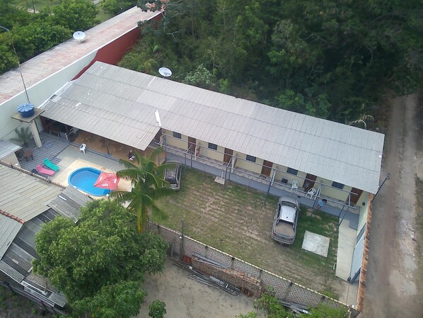 A building with a swimming pool, a fenced parking area, and a satellite dish.