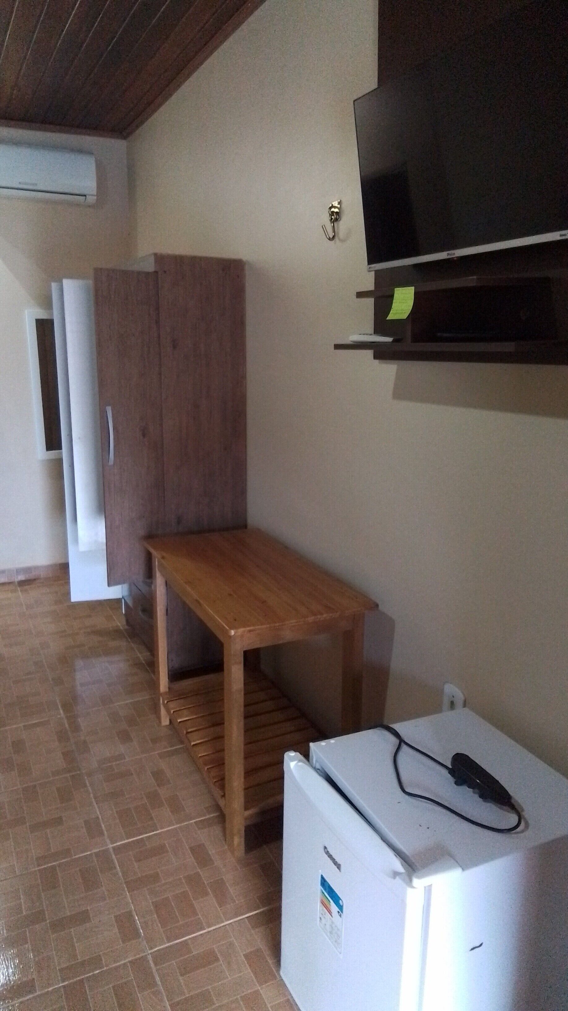 Una cocina compacta con una mesa de madera, un refrigerador blanco y un televisor montado en la pared.