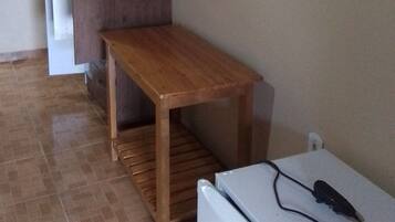 Una cocina compacta con una mesa de madera, un refrigerador blanco y un televisor montado en la pared.