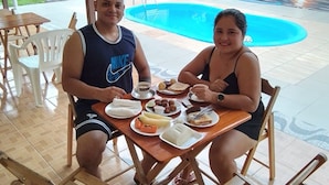 A dining area with a poolside view, featuring a mural with butterflies and flowers. - Pousada Sossego Ronaldo e Clarinha  (Santarem)
