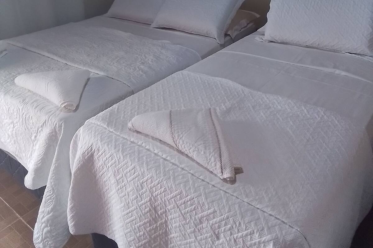 Une chambre d’hôtel avec deux lits, chacun étant équipé de draps et d’oreillers blancs.