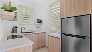 Eine moderne Küche mit einem Edelstahlkühlschrank, Holzschränken, einer Mikrowelle und einem Spülbecken.