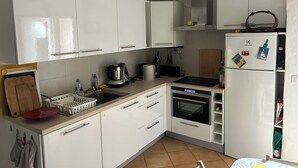 Una cocina moderna con armarios blancos, horno empotrado, refrigerador y varios electrodomésticos.