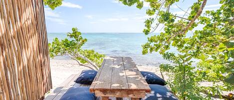 A wooden bench with cushions at a beachside location.