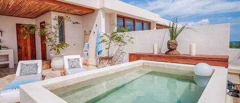 A modern outdoor pool area with lounge chairs, a wooden deck, and potted plants.