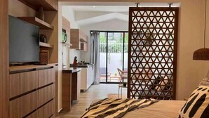 Ein modernes Schlafzimmer mit einem Bett, einem Fernseher und einer Schiebetür, die auf einen Balkon führt.
