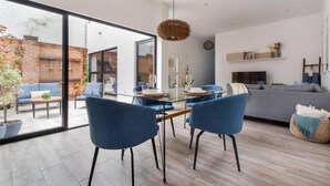 Ein modernes Wohnzimmer mit einem Glastisch, blauen Stühlen, einem grauen Sofa und einem Fernseher.