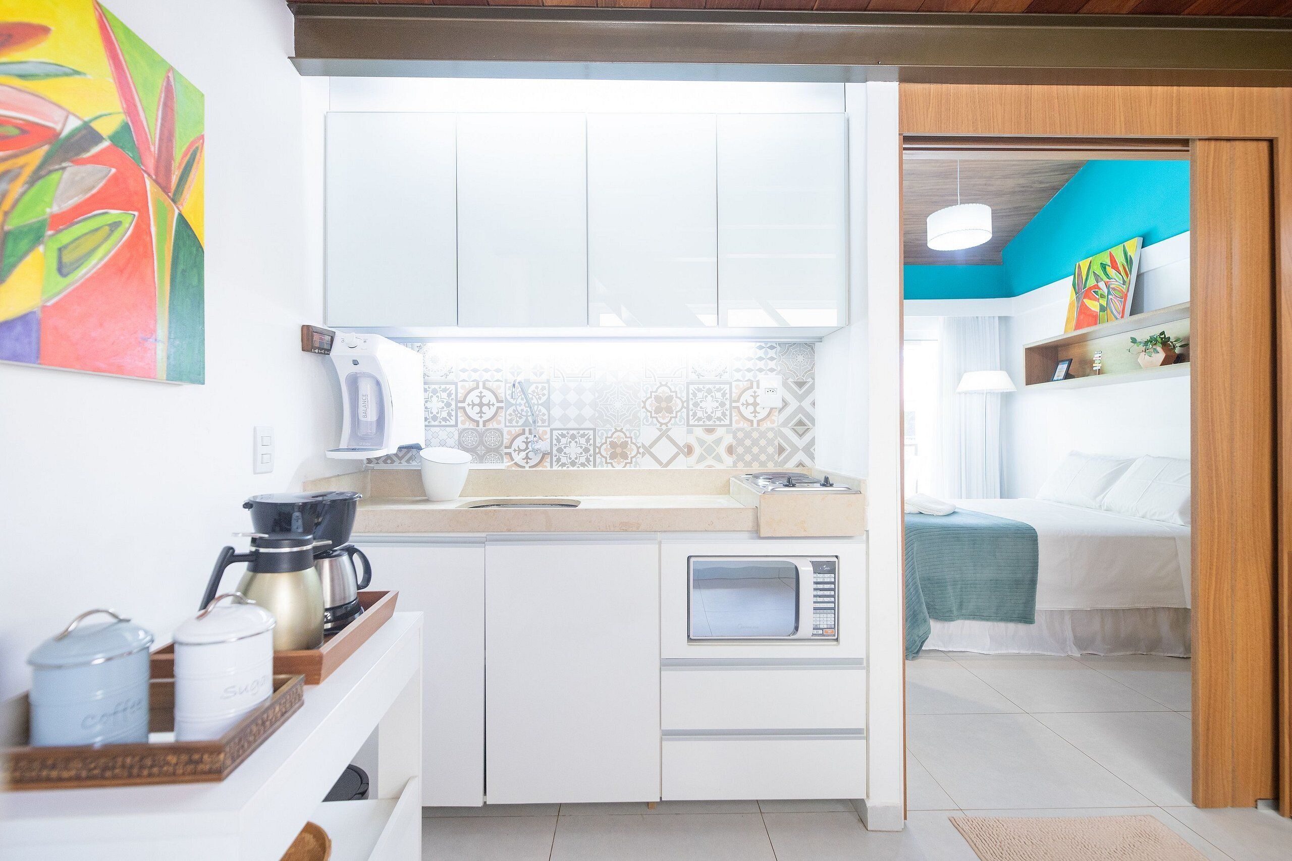 Uma cozinha compacta com micro-ondas, cafeteira e uma bandeja com recipientes.