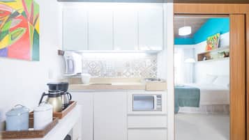 A compact kitchen with a microwave, coffee maker, and a tray with containers.