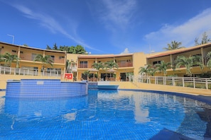 Un hôtel doté d’une piscine, de balcons et de palmiers.