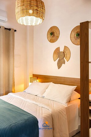 A neatly made bed with white bedding, a woven wall hanging, and a ceiling light fixture. - Solar Água Pipa (Tibau do Sul)