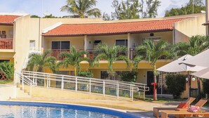 A hotel with a swimming pool, outdoor seating, and a red-tiled roof. - Solar Água Pipa (Tibau do Sul)