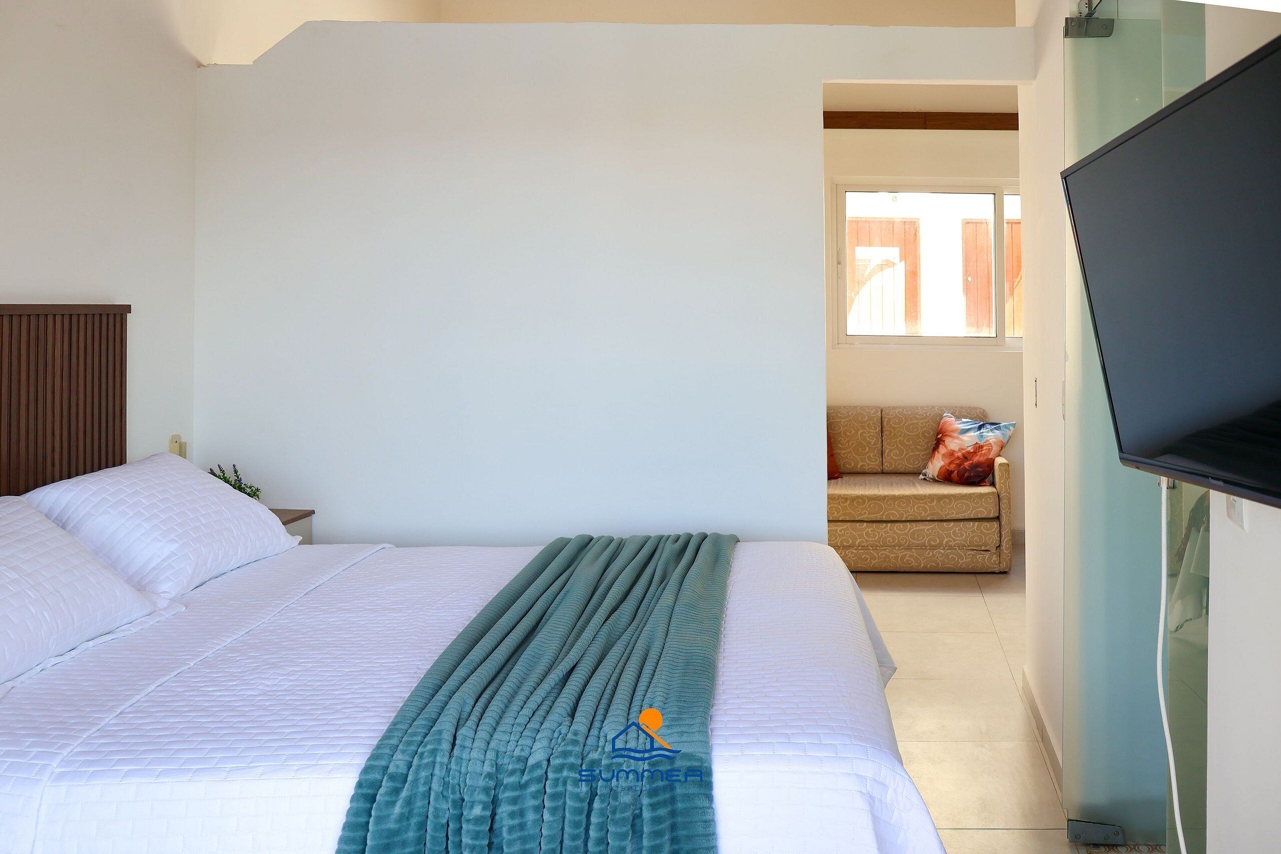 Une chambre à coucher avec un lit, une télévision, un canapé et une fenêtre.