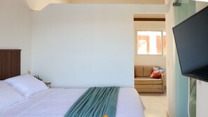 A bedroom with a bed, a television, a sofa, and a window. - Solar Água Pipa (Tibau do Sul)