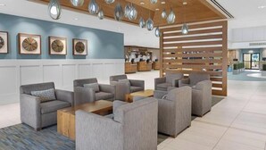 Un vestíbulo moderno con sofás grises, un mostrador de recepción de madera y una zona de recepción al fondo.