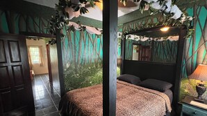 A bedroom with a bed, a nightstand, and a wall mural. - RAINFOREST ROOM - Close to Beach - One Bedroom Suite (San Pedro)