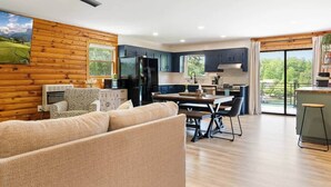 A modern kitchen with a dining area, wooden walls, and a large window. - Johnsons Cove - Lakefront Retreat With EV Charger (Seneca)