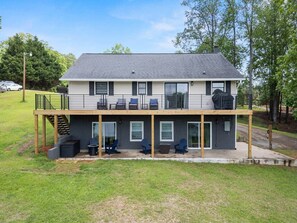 Ein zweistöckiges Haus mit überdachter Terrasse, Sitzgelegenheiten im Freien und einer Garage.