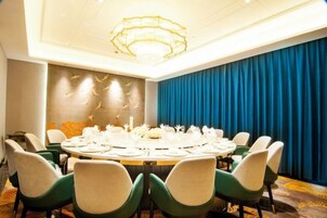Un salón de conferencias con una mesa redonda, sillas y una araña.