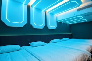 Habitación de hotel con diseño moderno, que incluye una cama con ropa blanca y un cabecero con iluminación integrada.