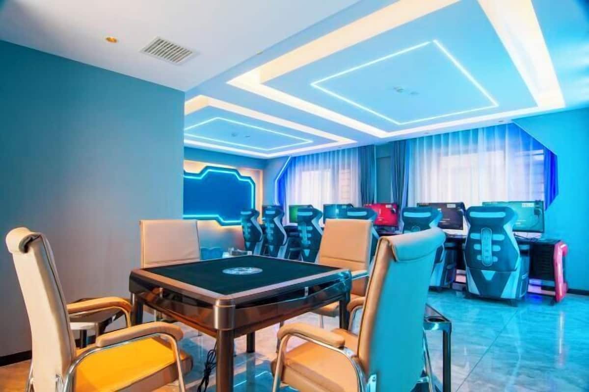 A modern room with a gaming area featuring multiple gaming stations and a pool table.
