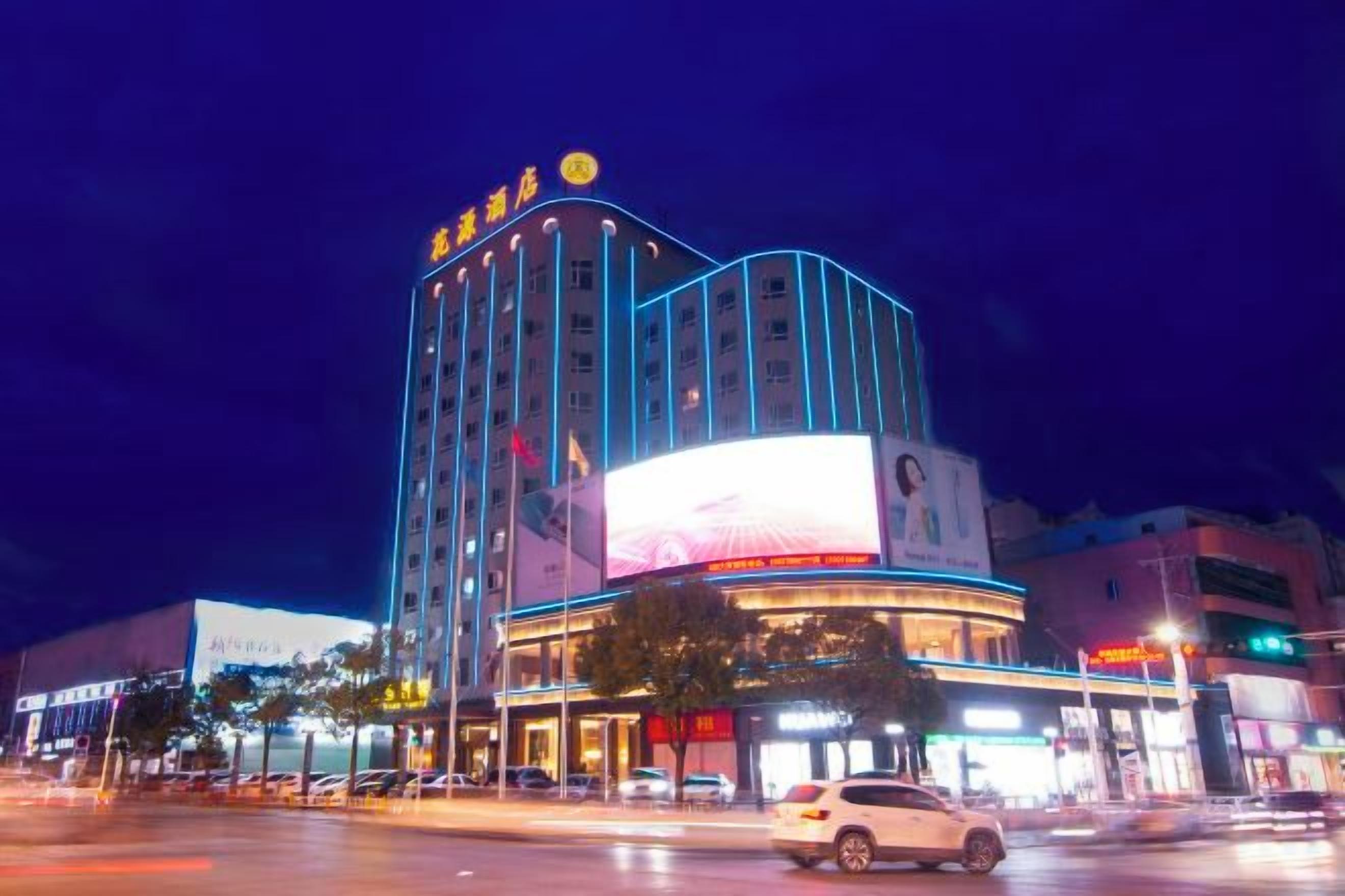 A multi-story hotel with a prominent curved facade, large illuminated signage, and a visible entrance with a glass front.