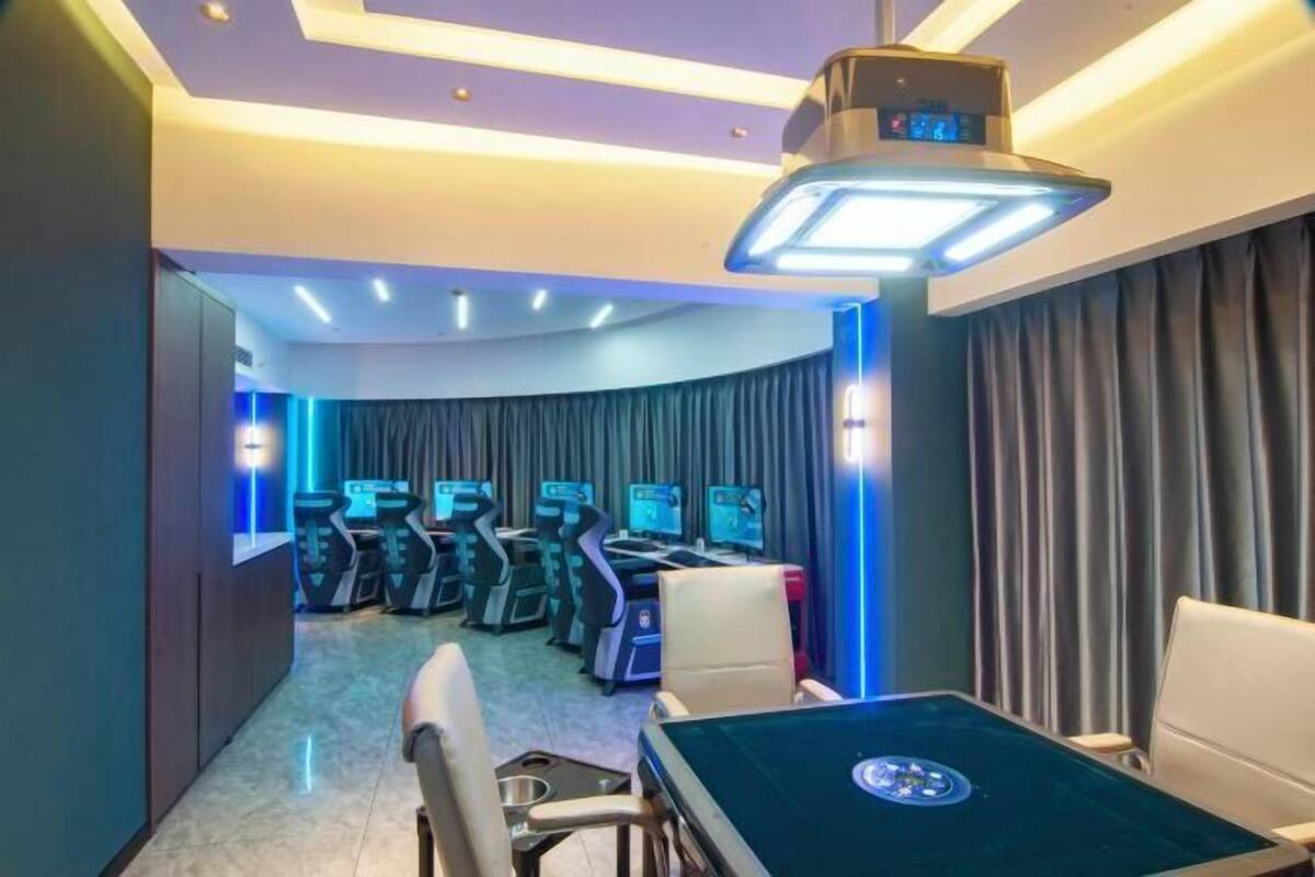 A gaming room with multiple gaming stations, a table with a circular design, and a ceiling light fixture.