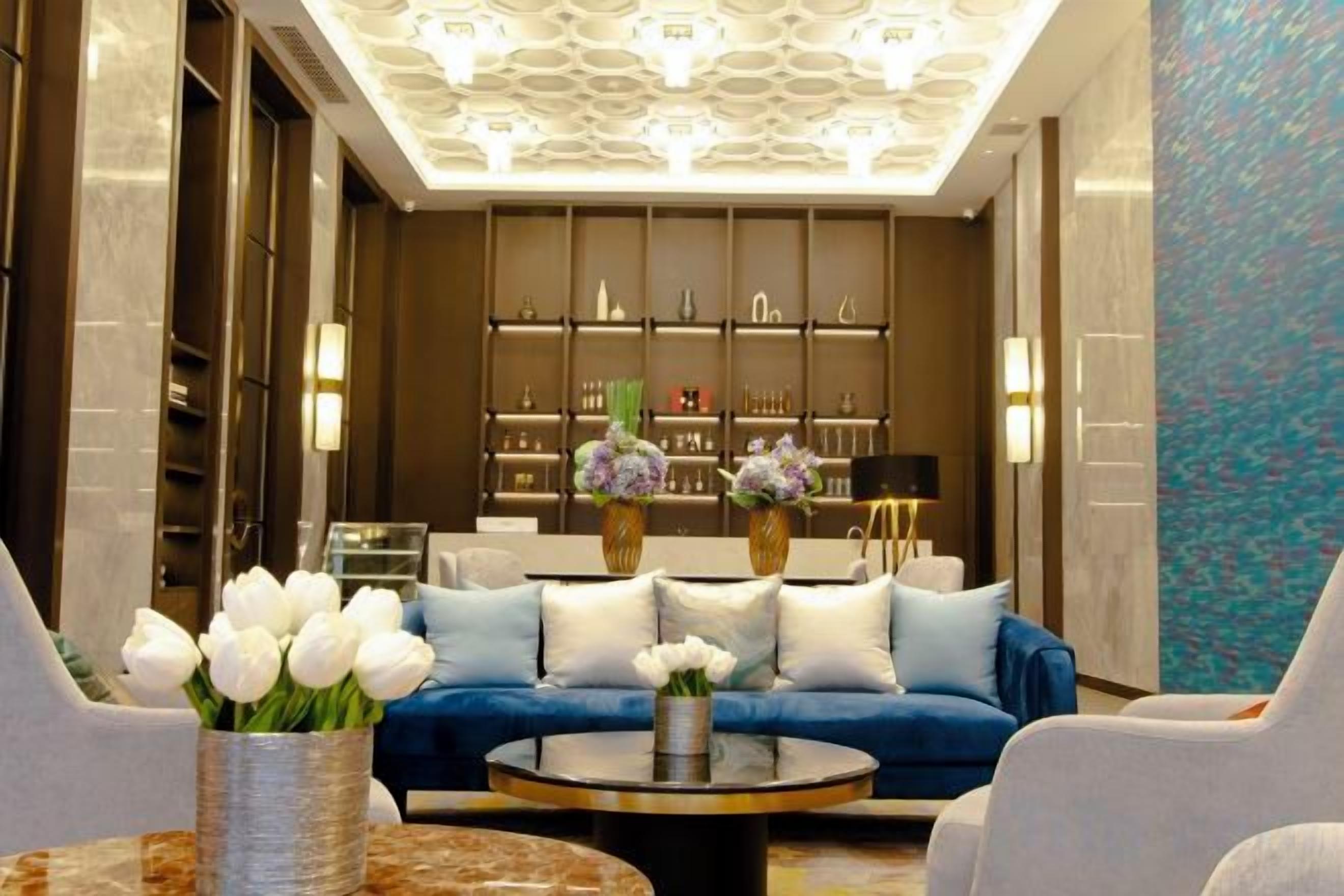 A modern lobby with a blue sofa, round coffee table, and vases of flowers.