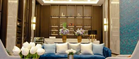 A modern lobby with a blue sofa, round coffee table, and vases of flowers.