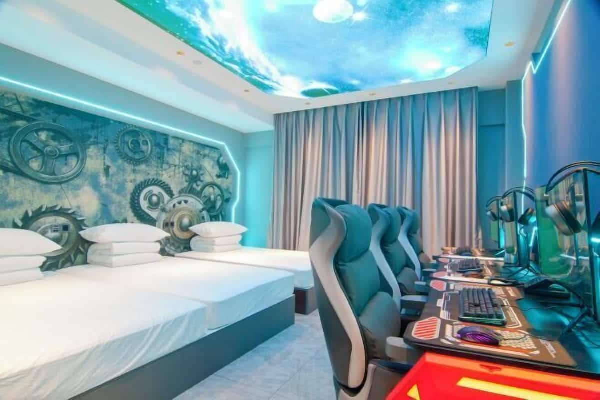 A modern room with a bed, a desk with a computer, and a ceiling with a mechanical design.