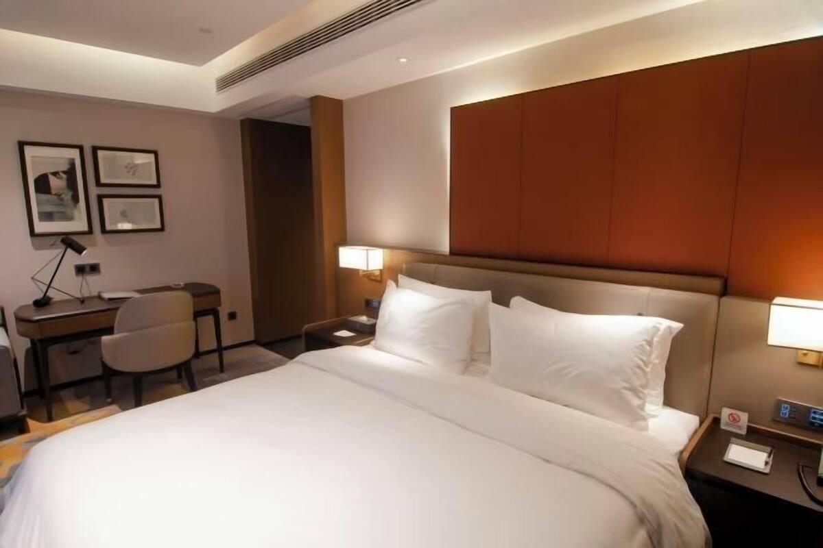 A hotel room with a large bed, a desk, and a chair.