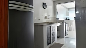 Een moderne keuken met een zwarte koelkast, witte kastjes en een betegelde vloer.