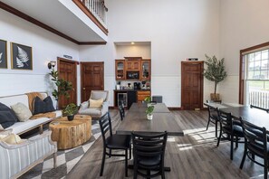 Un vaste salon doté d’une grande table à manger, d’un coin cuisine avec des meubles en bois et d’un escalier menant à l’étage supérieur.