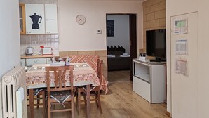 Een compacte woonruimte met een eethoek, kitchenette en televisie.