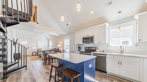 Una cucina moderna con isola centrale, sgabelli da bar e piano cottura in acciaio inossidabile.