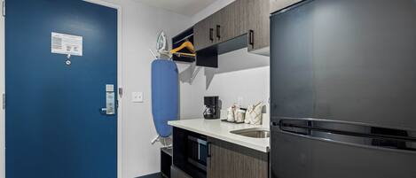 Una cucina compatta con una porta blu, un frigorifero in acciaio inossidabile e una macchina da caffè sul ripiano.