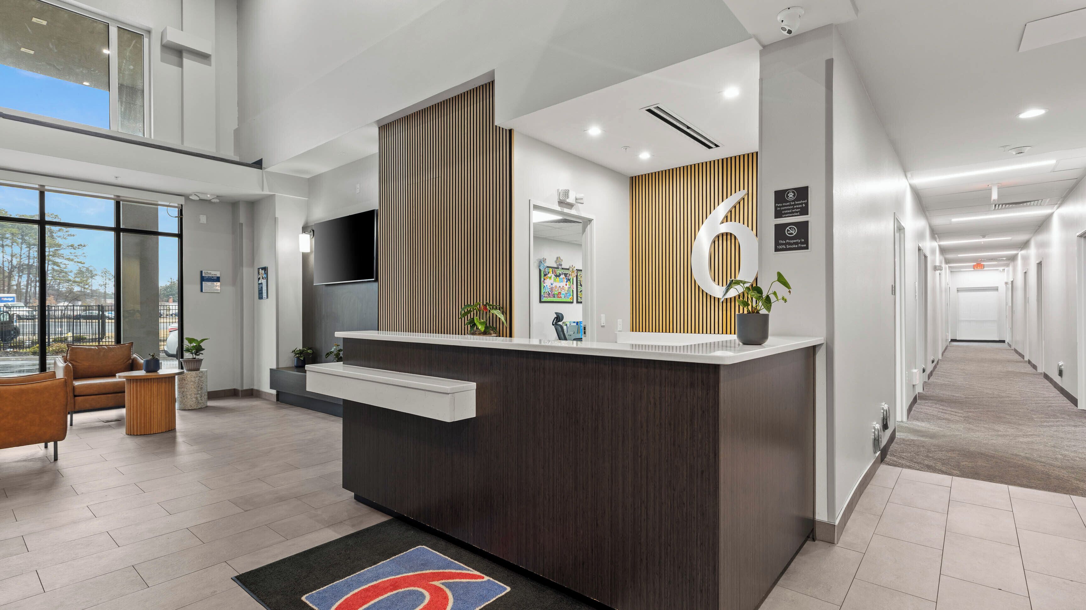 A reception desk with a modern design, a large window, and a hallway leading to other areas.