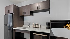 Una cocina moderna con armarios de madera oscura, un refrigerador de acero inoxidable, un fregadero y una cafetera.