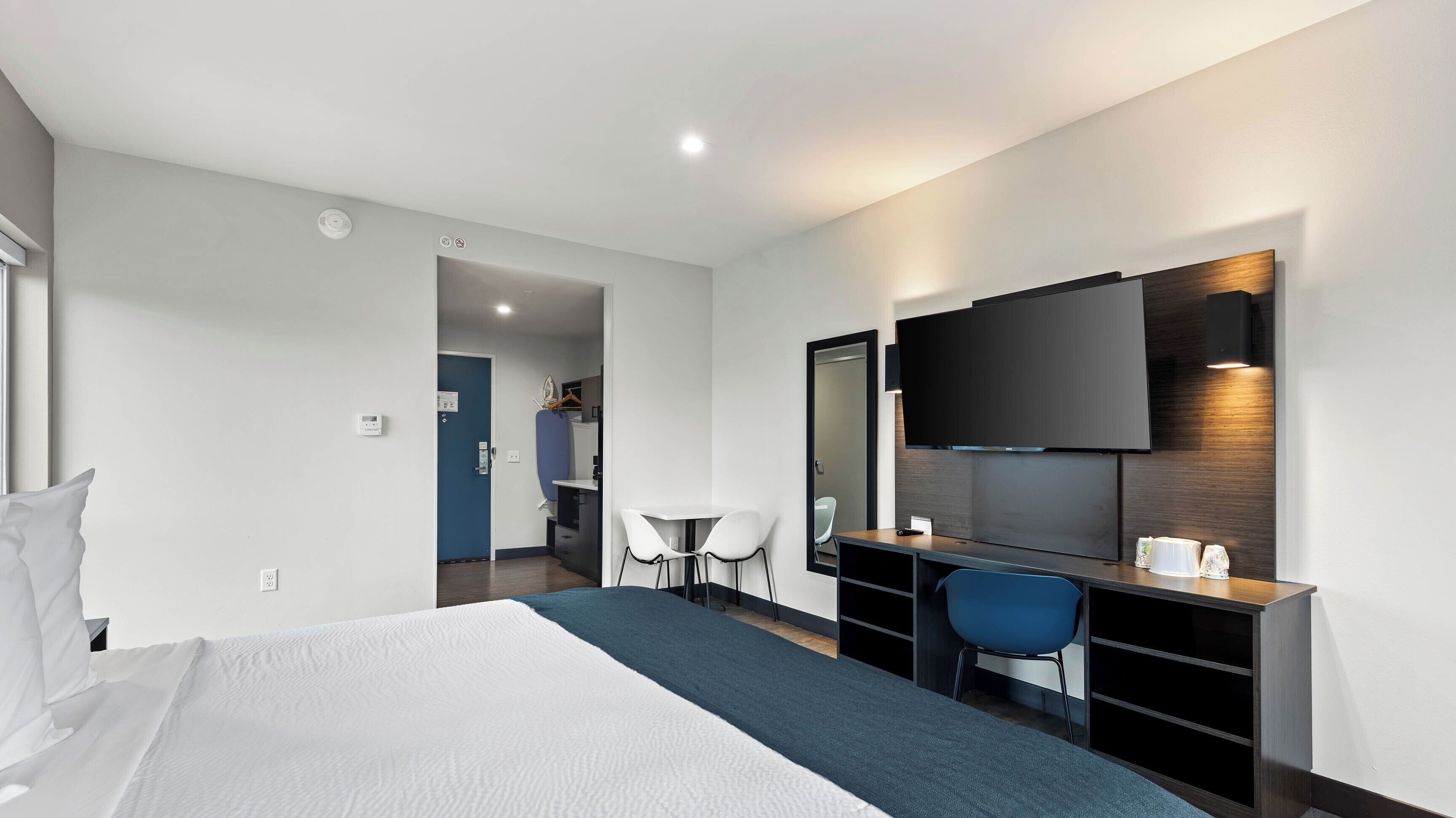 Une chambre d’hôtel comprenant un lit, un bureau avec une chaise, une télévision et une petite table.