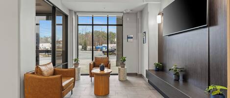 A modern lobby with leather sofas, a round wooden table, and potted plants.