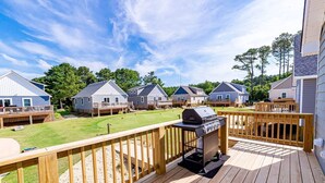Une terrasse avec un barbecue, entourée de maisons dotées de terrasses et d’une pelouse.