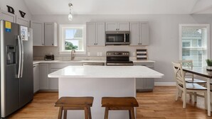 A modern kitchen with a central island, stainless steel appliances, and wooden stools.