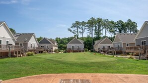 A residential area with houses, a grassy lawn, and a patio with chairs and a table.
